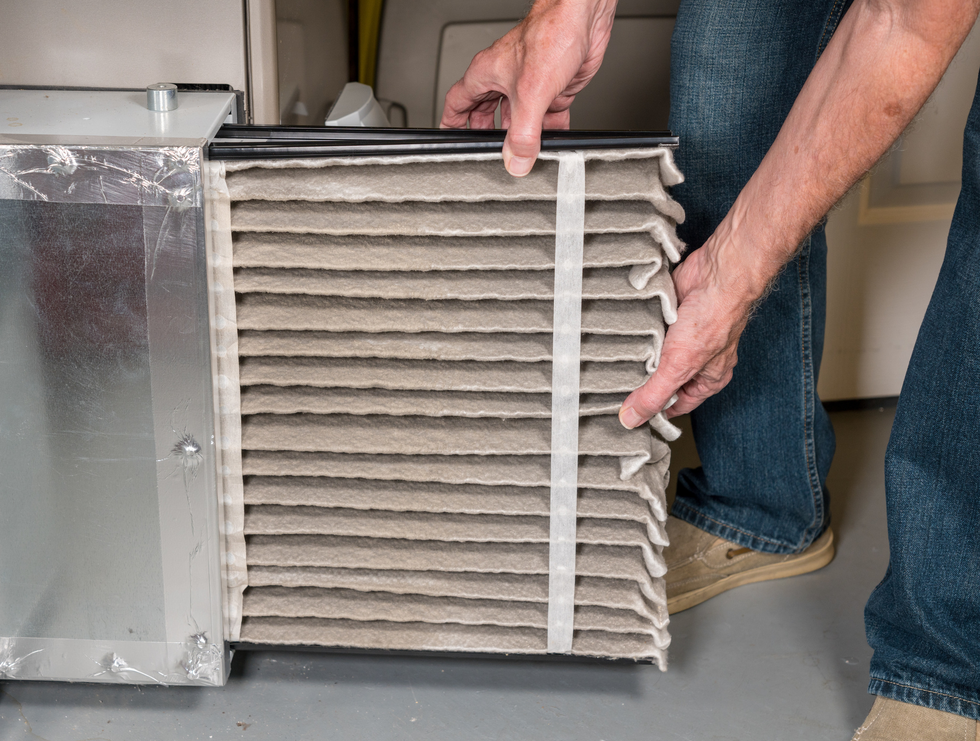 Senior man changing a dirty air filter in a HVAC Furnace