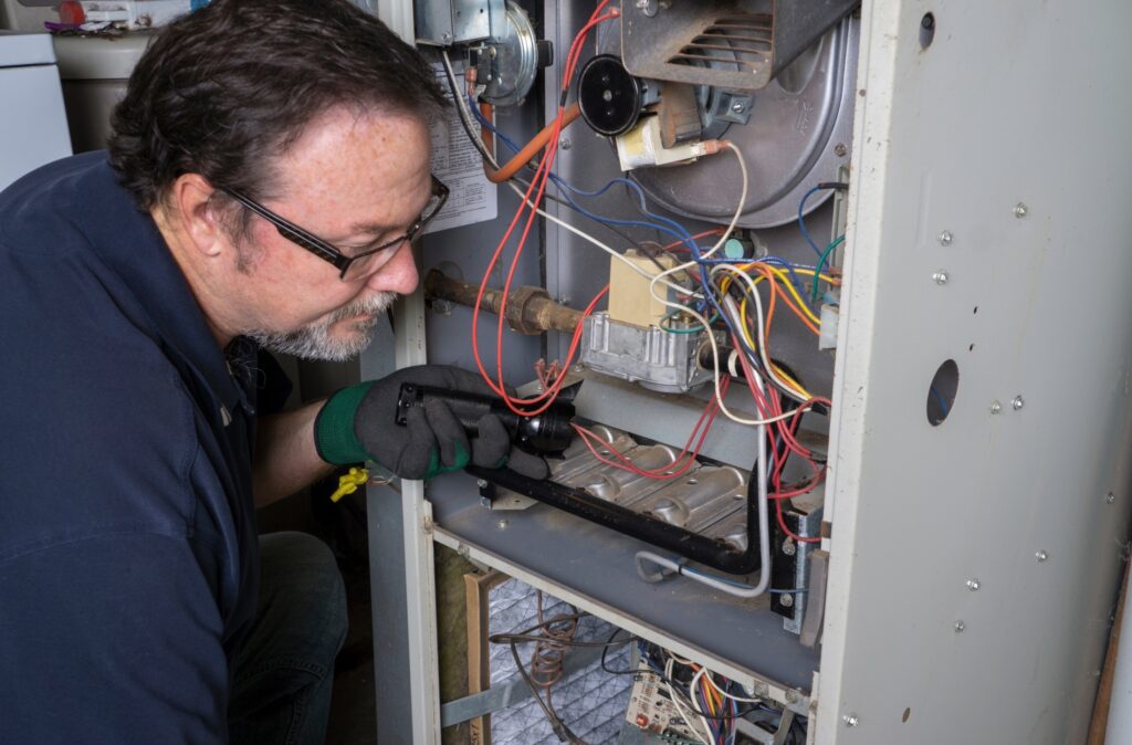 A man diligently operates a furnace in a residential setting, ensuring warmth and comfort in the home.